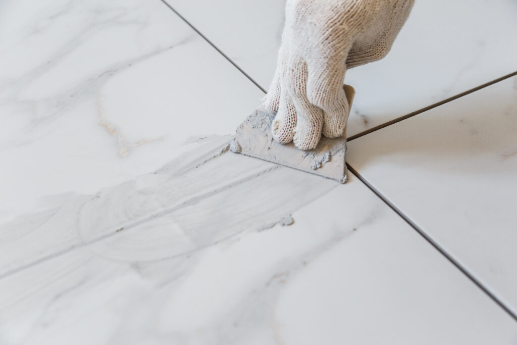 Grouting Tiles Seams With A Rubber Trowel.